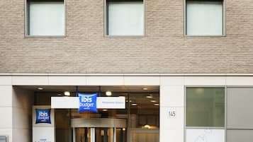 L'ingresso di un hotel con una insegna per ibis budget, un ingresso girevole e il numero 145 sulla parete.