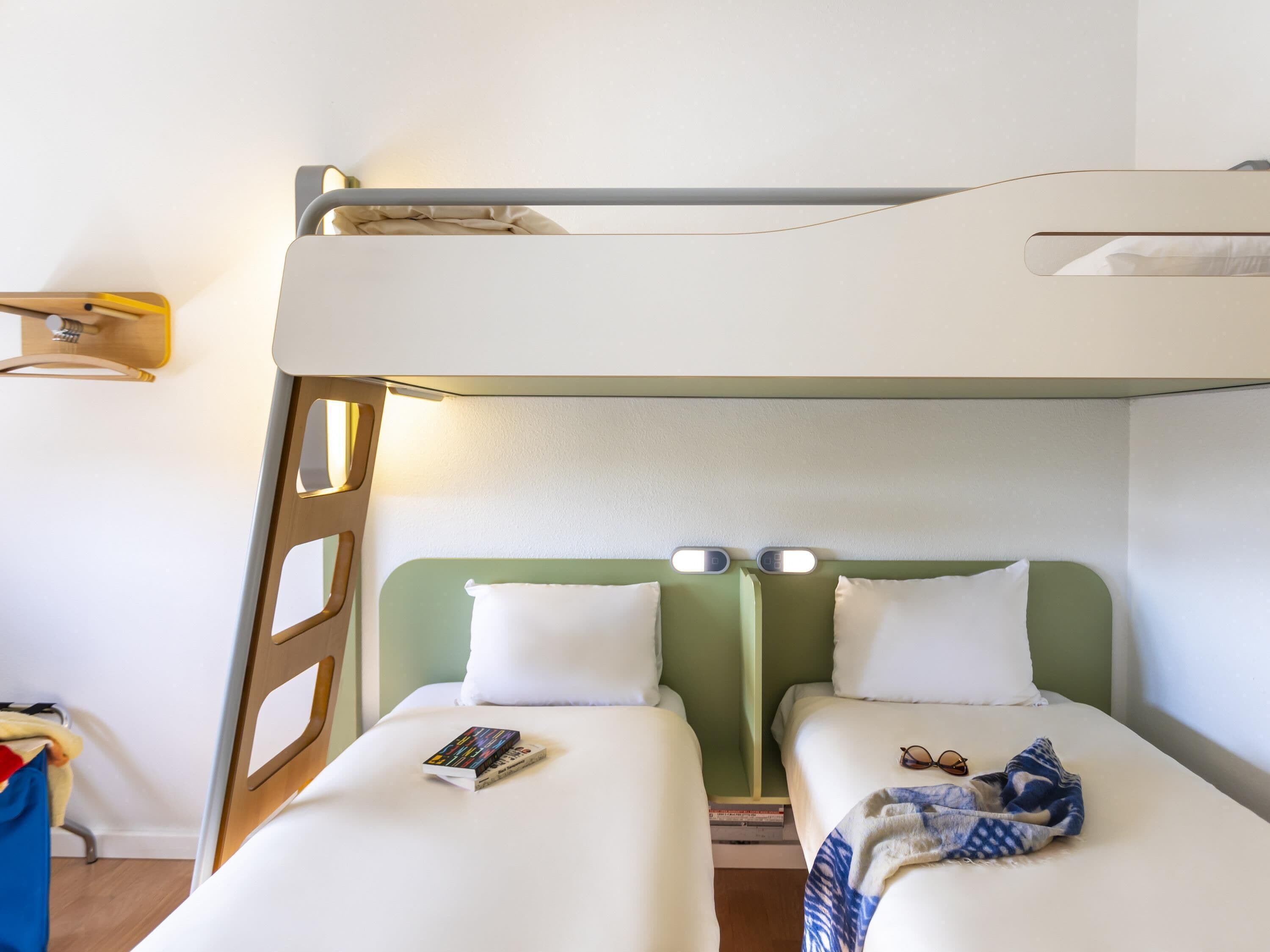 Una cama litera con dos almohadas, un par de gafas y una manta en la cama inferior.