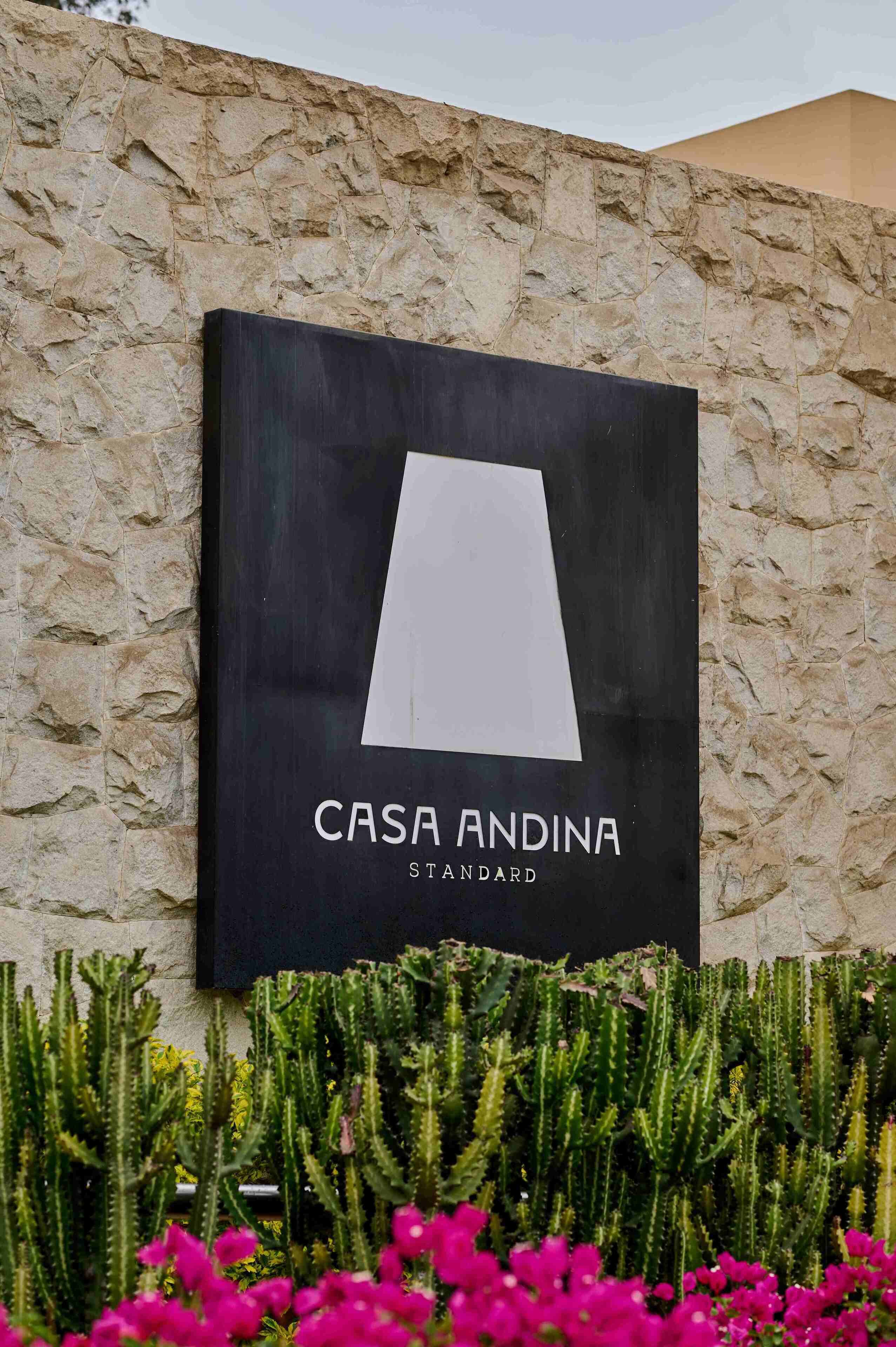Señal de 'Casa Andina Standard' con un jardín de cactus al frente.