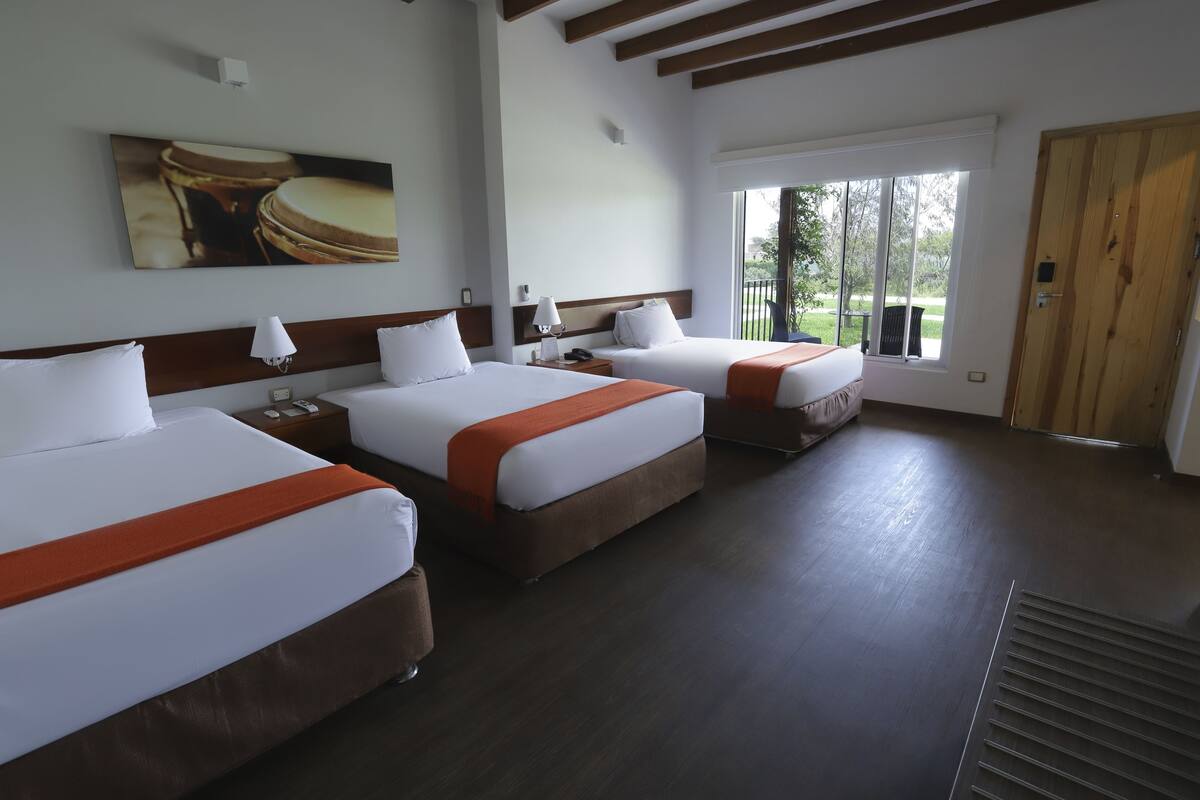 Habitación de hotel con dos camas, un ventanal grande y una puerta.