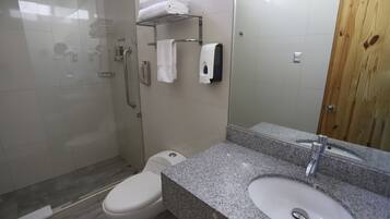 Un baño con ducha, inodoro, lavamanos y puerta de madera.