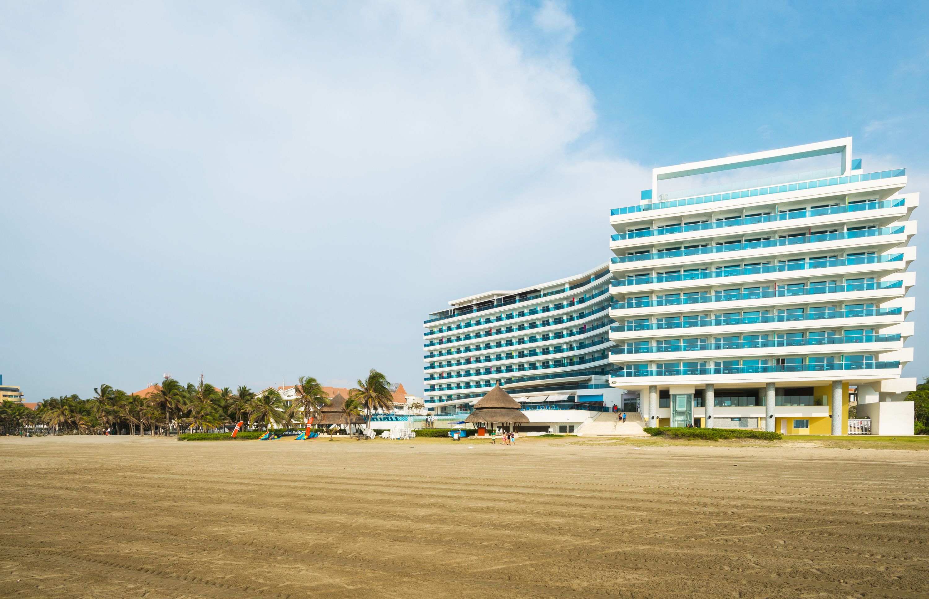 Un hotel moderno con varios pisos, amplias ventanas y vista al mar.
