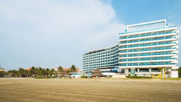 Un hotel moderno con varios pisos, amplias ventanas y vista al mar.
