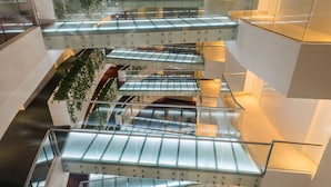 A multi-level atrium with glass railings and greenery.