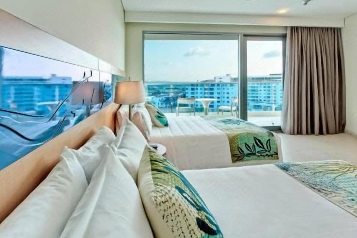 Una habitación de hotel con balcón, cama con vistas y ventilador de techo.