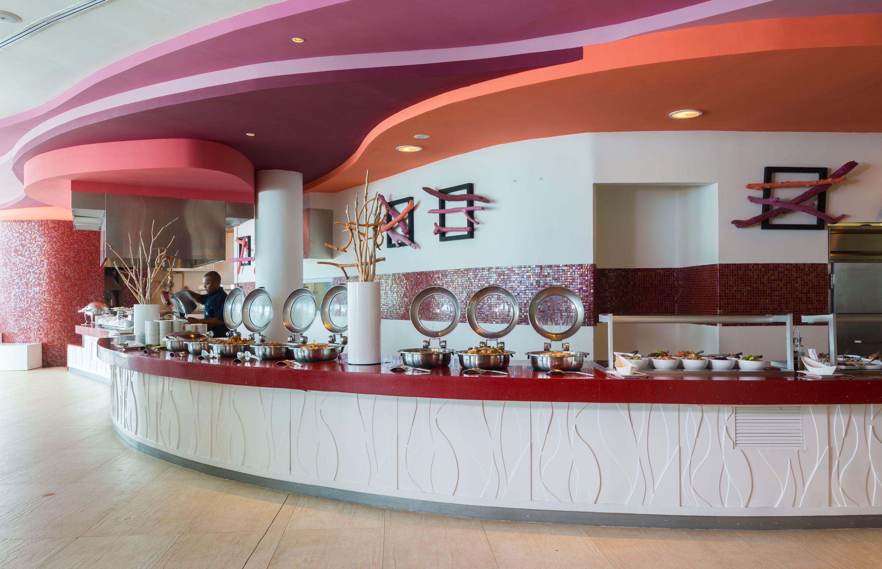 A buffet area with multiple serving stations, a central pillar, and decorative wall elements.