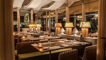A restaurant with multiple tables, each set with plates, glasses, and candles.