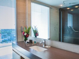 Un bagno moderno con uno specchio grande, un lavandino e una zona doccia.