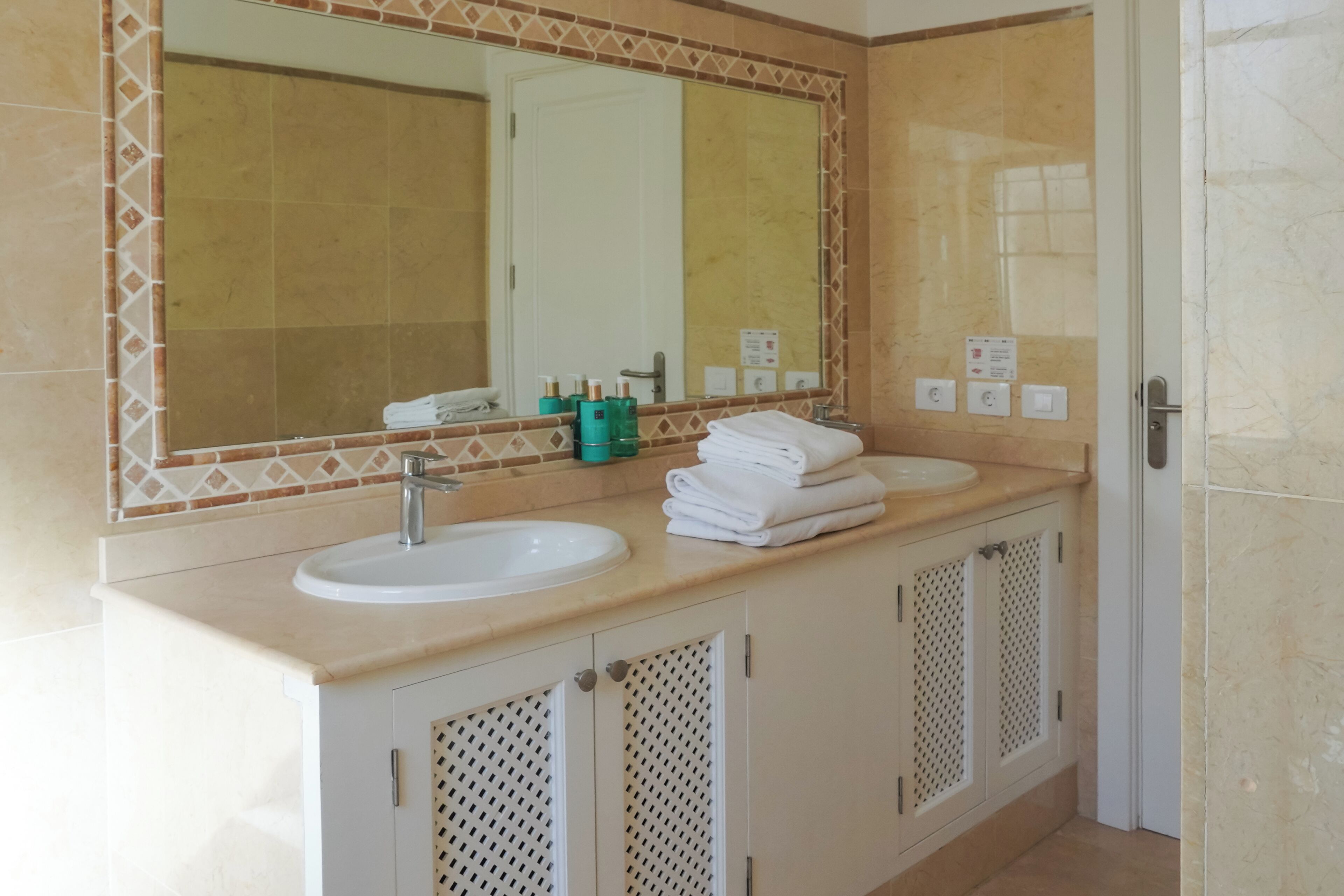A bathroom with two sinks, a large mirror, and a door.