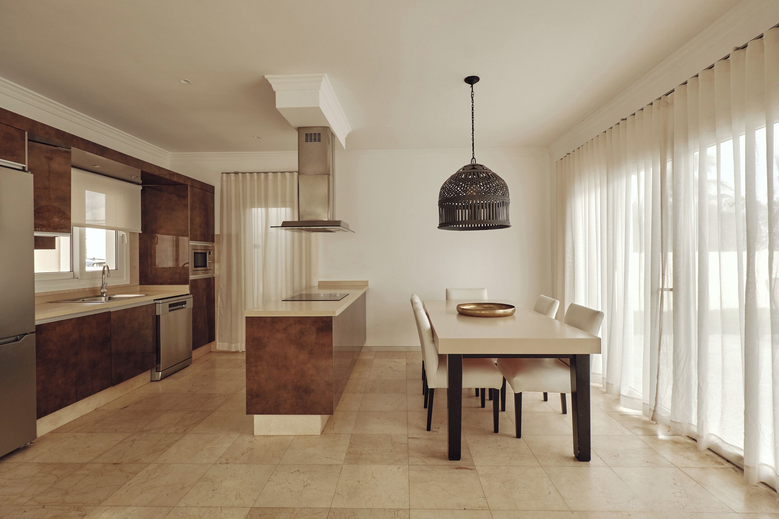 A modern kitchen with a central island, stainless steel appliances, and a dining area with a table and chairs.