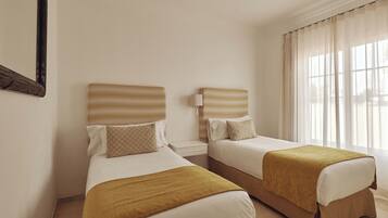A hotel room with two beds, each with a headboard and a bedside table.