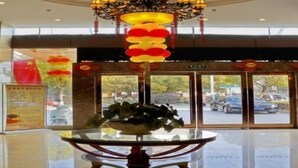 En entréhall med ett glasbord, en kristallkrona och utsikt över gatan utanför.