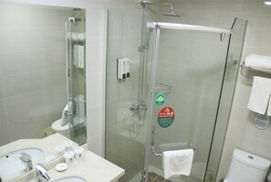 A modern bathroom with a glass-enclosed shower, a sink with toiletries, and a toilet.