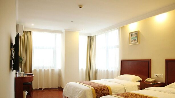 Habitación de hotel con dos camas, un escritorio, una silla, un televisor y una ventana con cortinas.