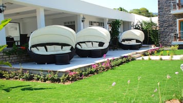 A modern house with three large, white, dome-shaped outdoor seating areas with cushions.