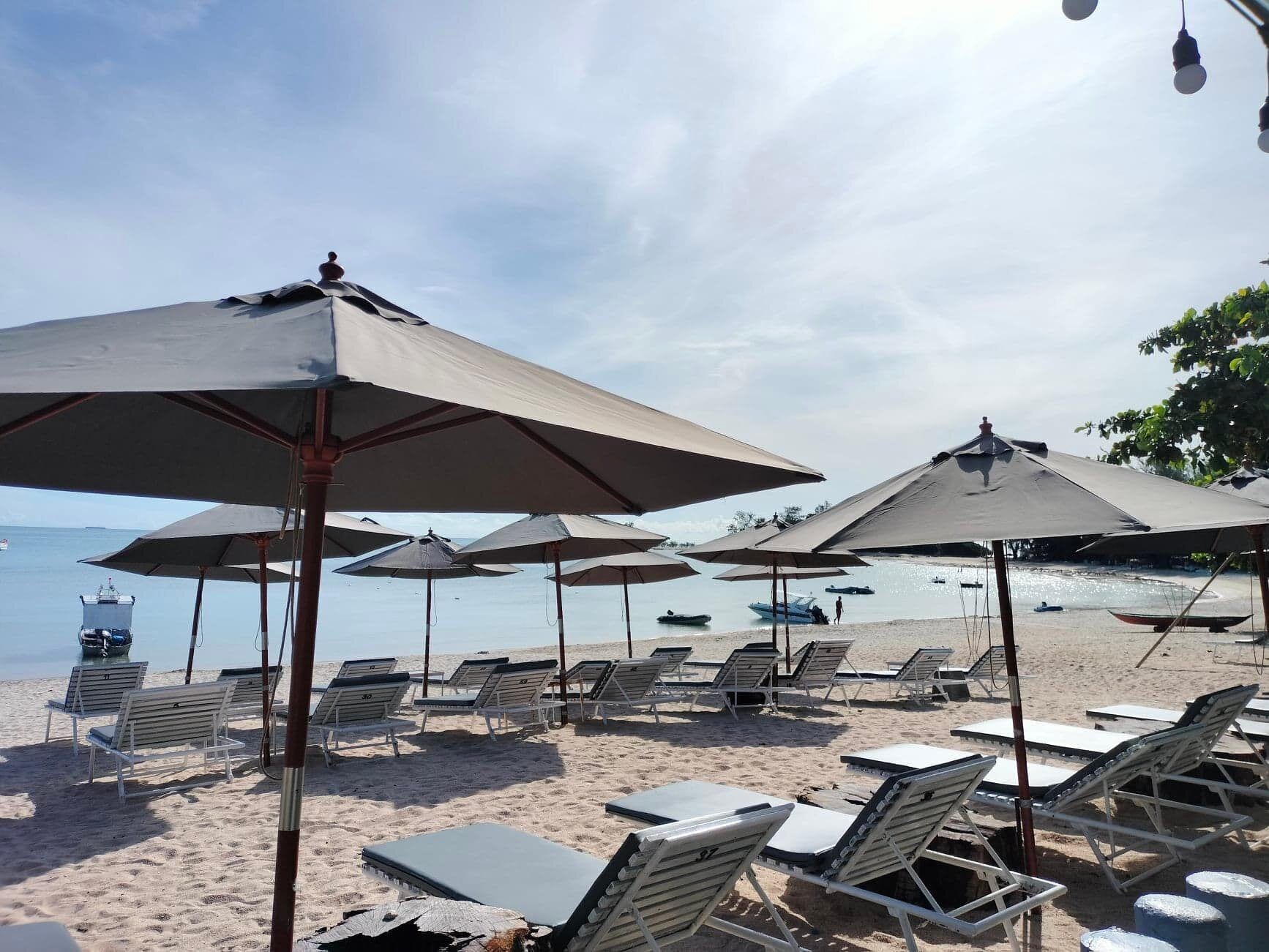 Une plage avec des parasols, des chaises longues et une vue sur la mer.