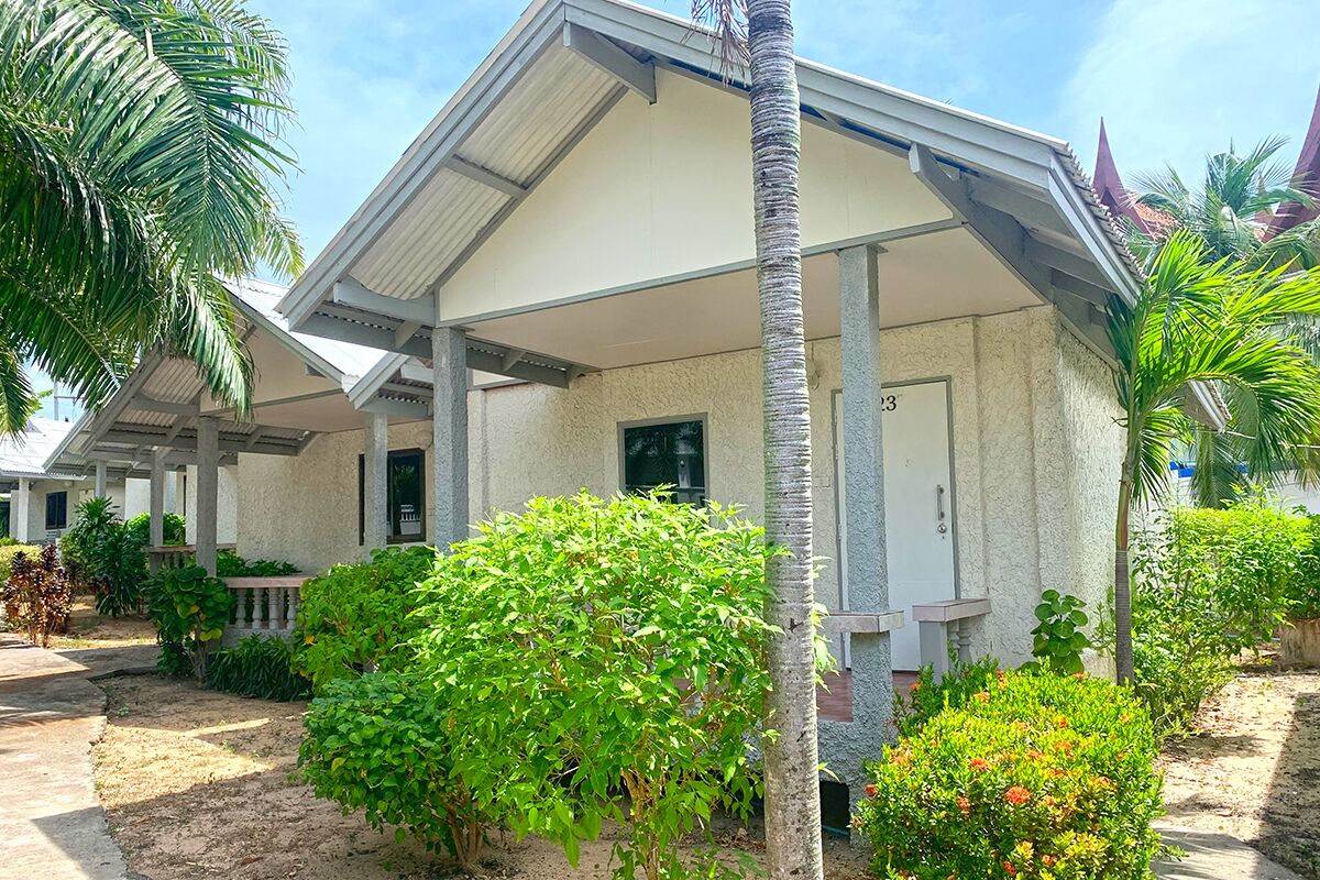 A building with a covered porch, palm trees, and a well-maintained garden.
