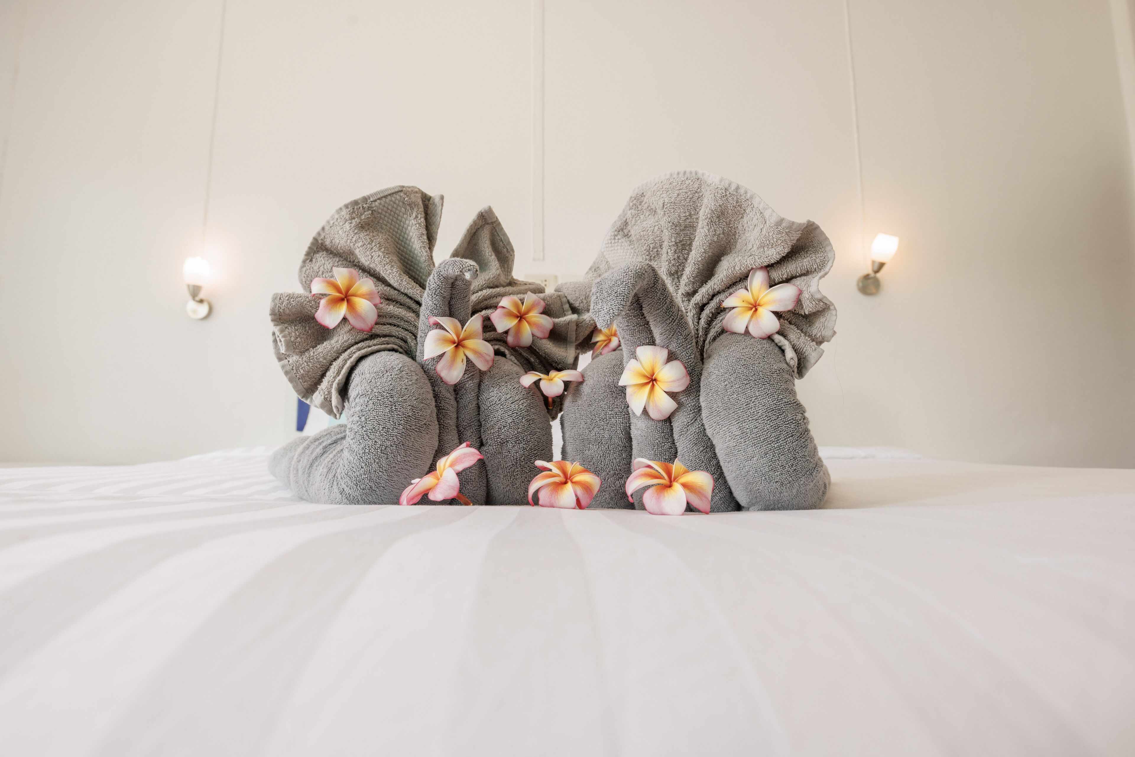 A bed with towels and flowers.