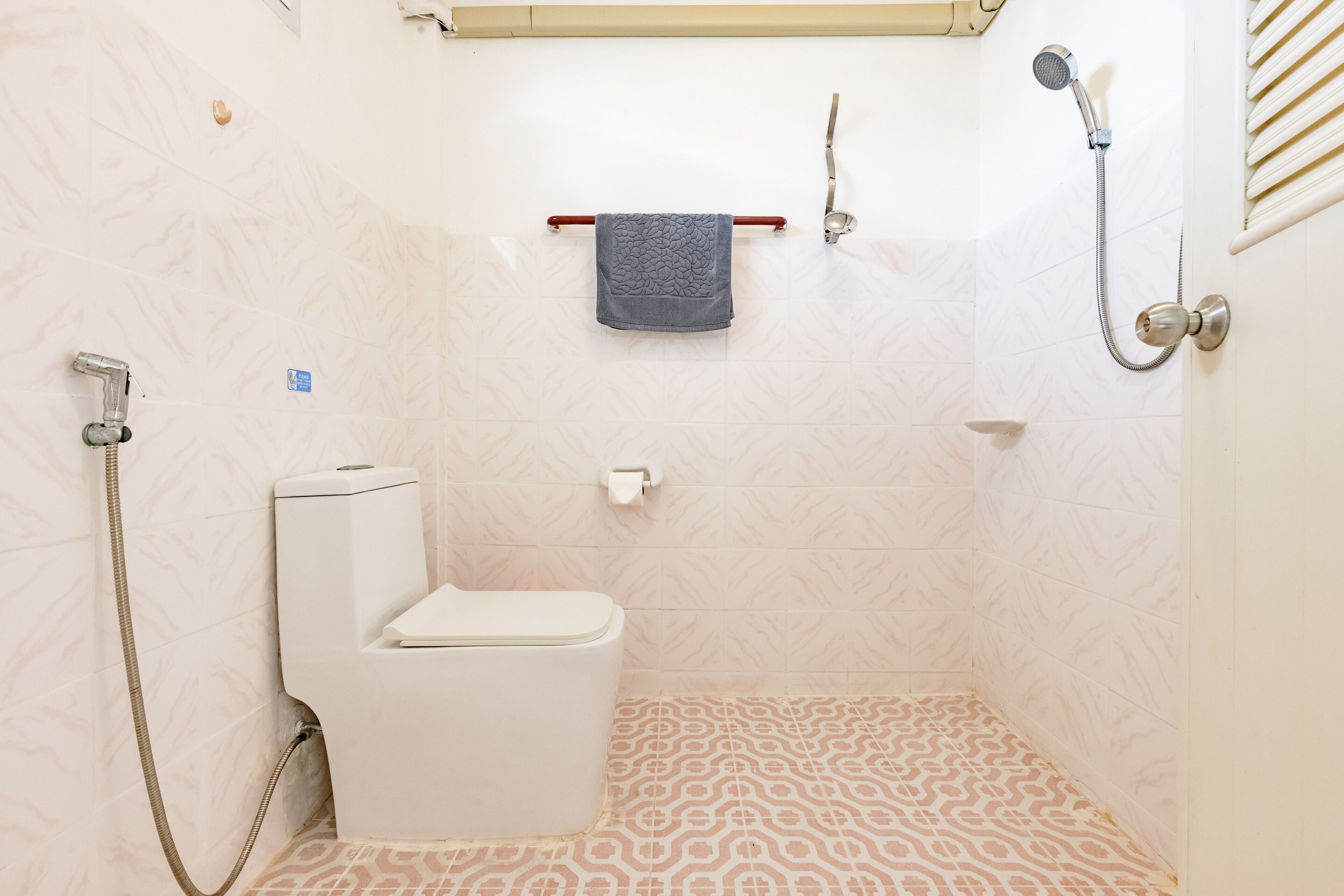 A bathroom with a toilet, shower, and towel rack.