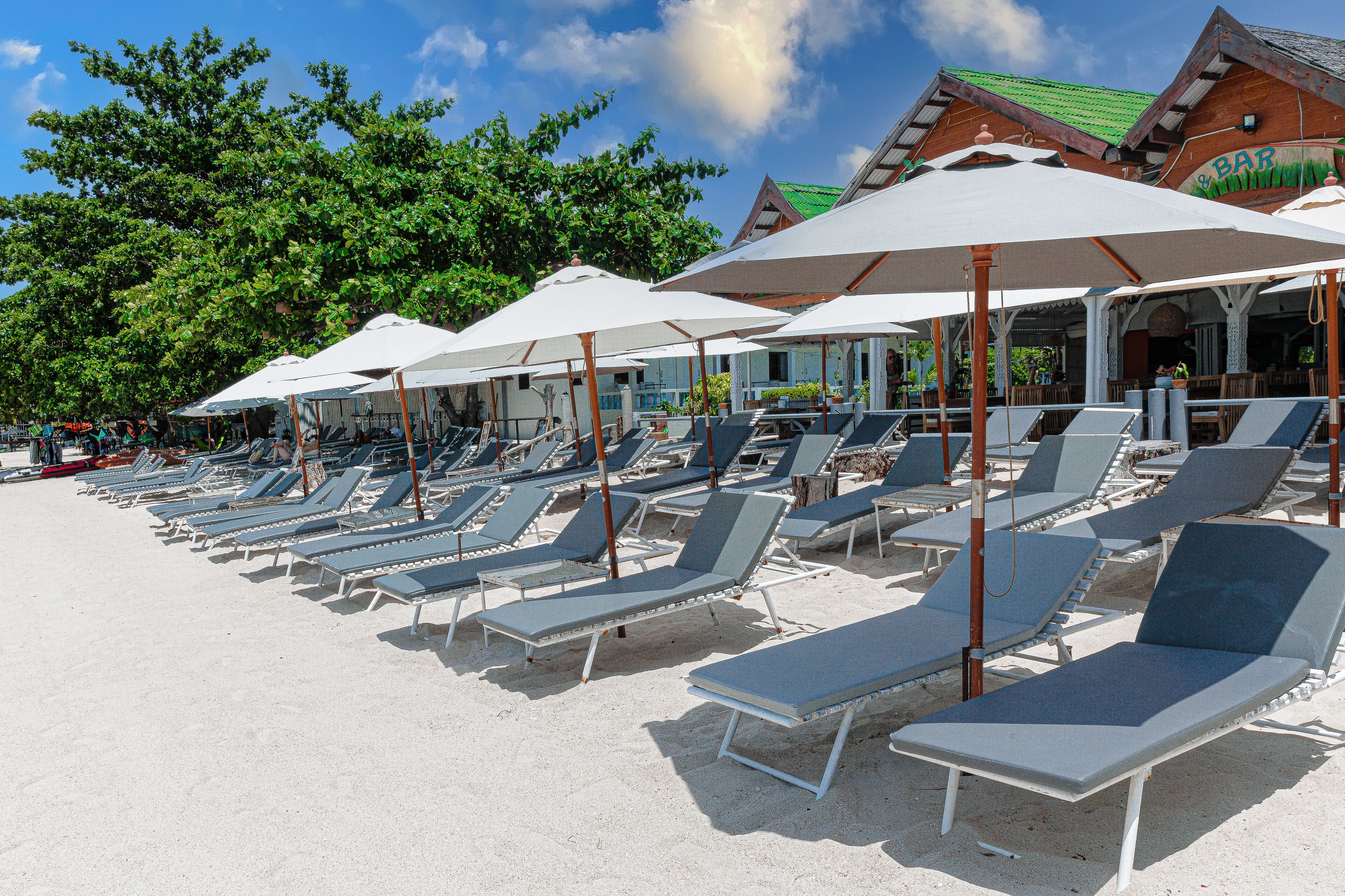 En la playa, arena blanca, sillas reclinables de playa, sombrillas