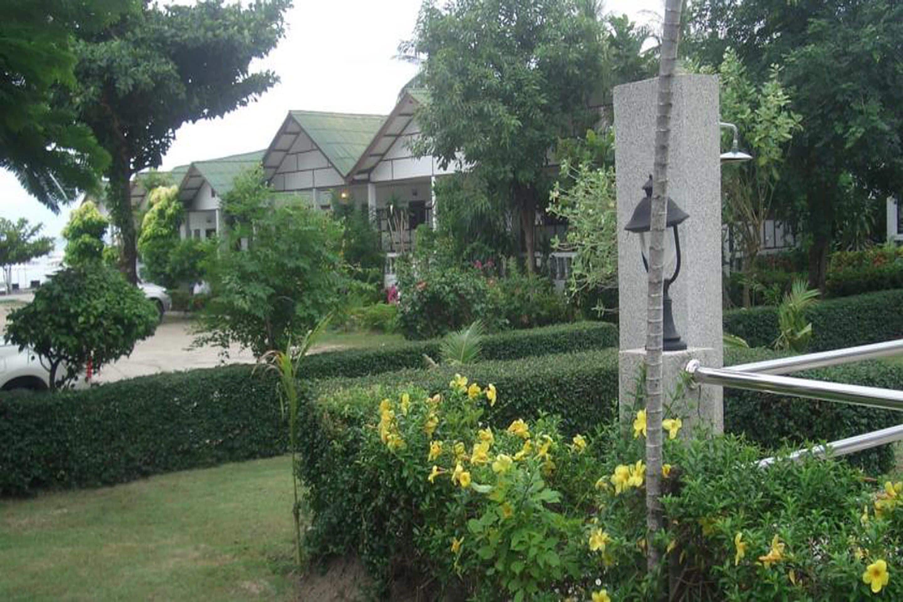 A landscaped garden with a pathway, a lamp post, and a building with a green roof in the background.