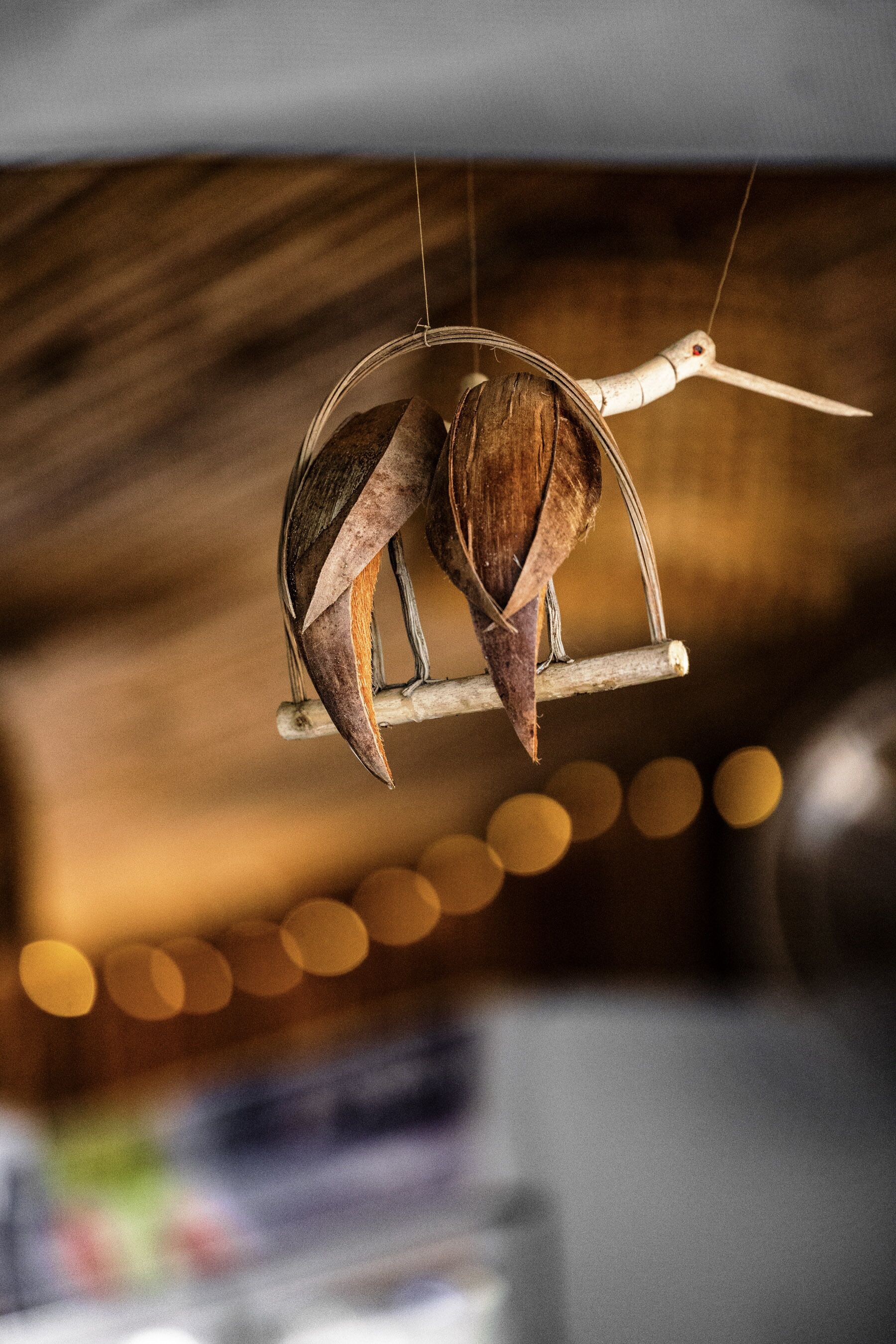Una jaula de pájaros con un posadero de madera y un pájaro colgando.