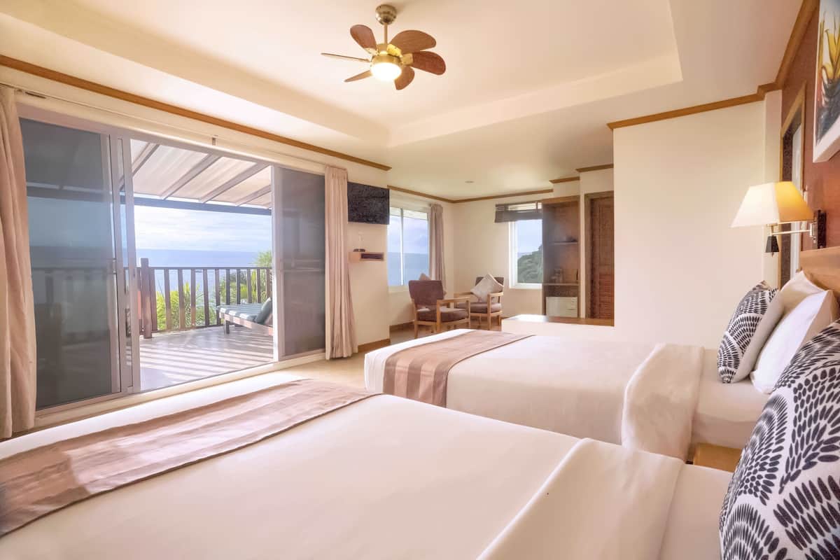 A hotel room with two beds, a balcony, a ceiling fan, and a chair.