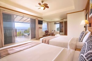 Ein Hotelzimmer mit zwei Betten, einem Balkon, einem Deckenventilator und einem Sessel.
