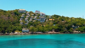 A coastal resort with multiple buildings on a hillside, overlooking turquoise waters.