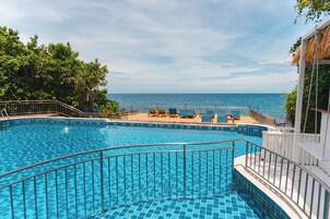 Una piscina al aire libre, sombrillas, sillones reclinables de piscina