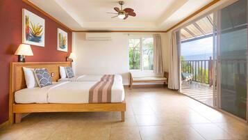 A hotel room with a large bed, a ceiling fan, a window with a view of the outdoors, and a balcony with a bench.