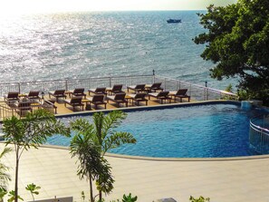 Una piscina al aire libre, sombrillas, sillones reclinables de piscina