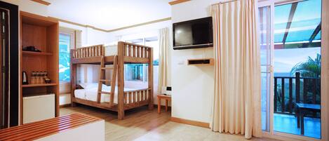 A room with bunk beds, a TV, a small table, and a balcony with a view.