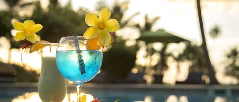 Zwei Cocktails mit tropischen Blumen auf einem Tisch am Pool.