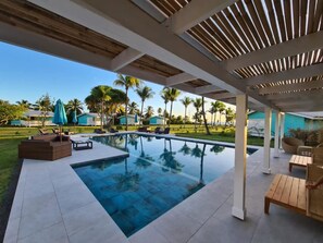 Un área de piscina moderna al aire libre con vistas despejadas del paisaje circundante, incluyendo palmeras y un edificio distante.