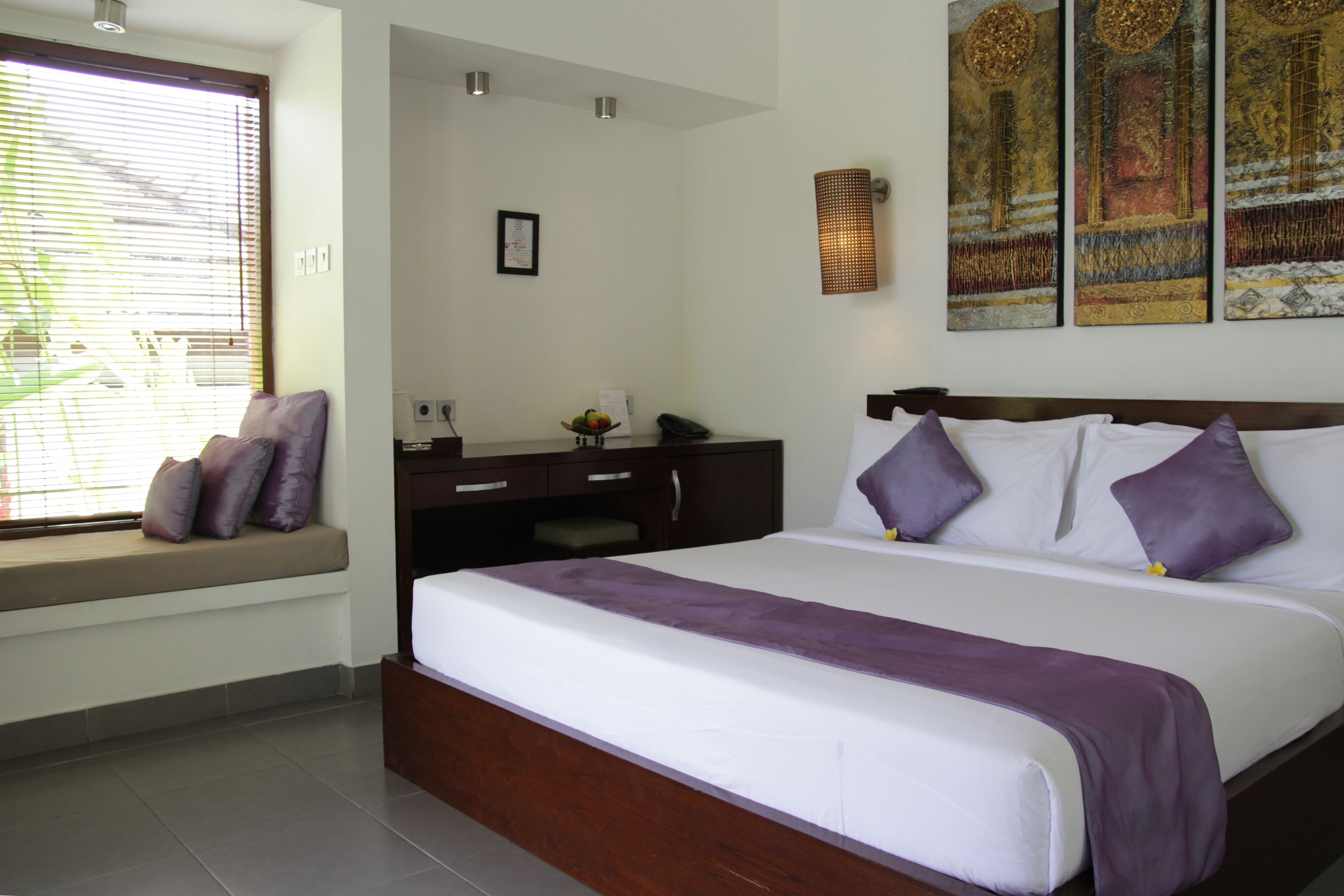 Ein Hotelzimmer mit einem großen Bett, einem fest eingebauten Schreibtisch, einem Fenster mit Ausblick und Kunstwerken an der Wand.