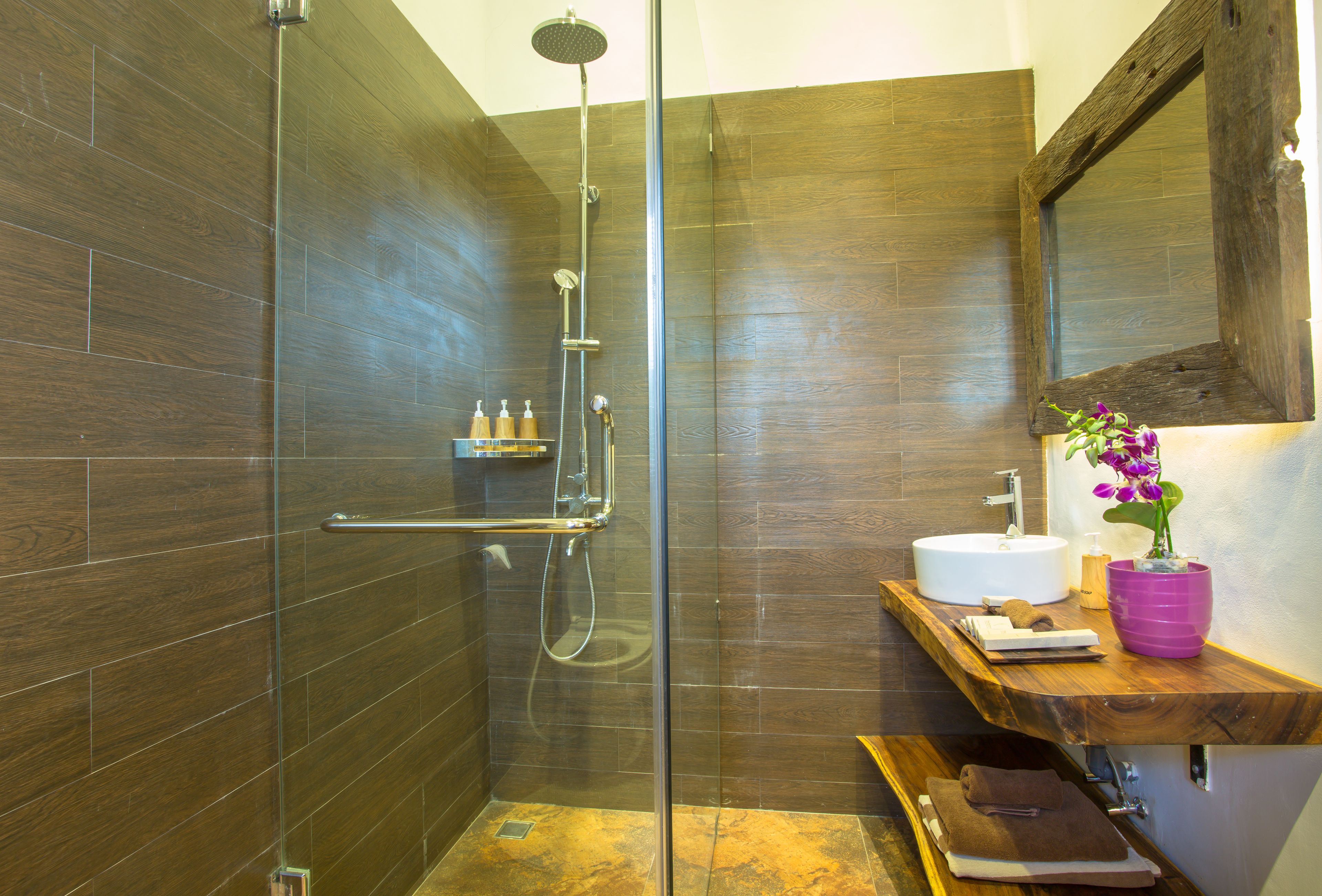 Une salle de bain moderne avec une douche à parois de verre, un meuble-lavabo en bois et un grand miroir.