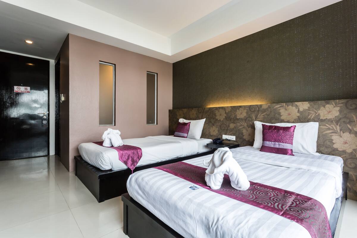 A hotel room with two beds, a large mirror, a dark textured wall, and a door with a 'No Entry' sign.