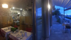 An outdoor dining area with tables and chairs, overlooking a lake and mountains. - Villa Edera (Malcesine)