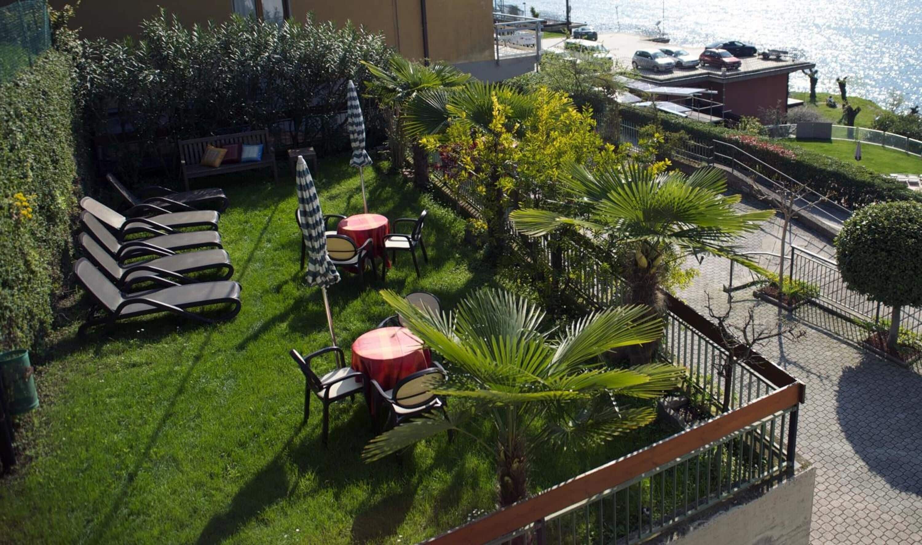 Un jardín en la azotea con mobiliario exterior, vistas al mar y un aparcamiento.