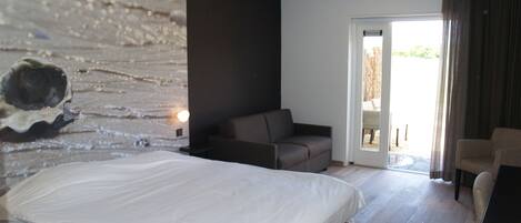 A modern bedroom with a large bed, a sofa, and a dining table.
