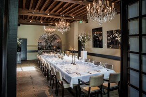 Una larga mesa de comedor lista para una comida, con candelabros y obras de arte enmarcadas en las paredes.