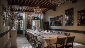 A long dining table set for a meal in a room with wooden floors, chandeliers, and framed artwork on the walls. - Fletcher Landgoedhotel Renesse (Renesse)