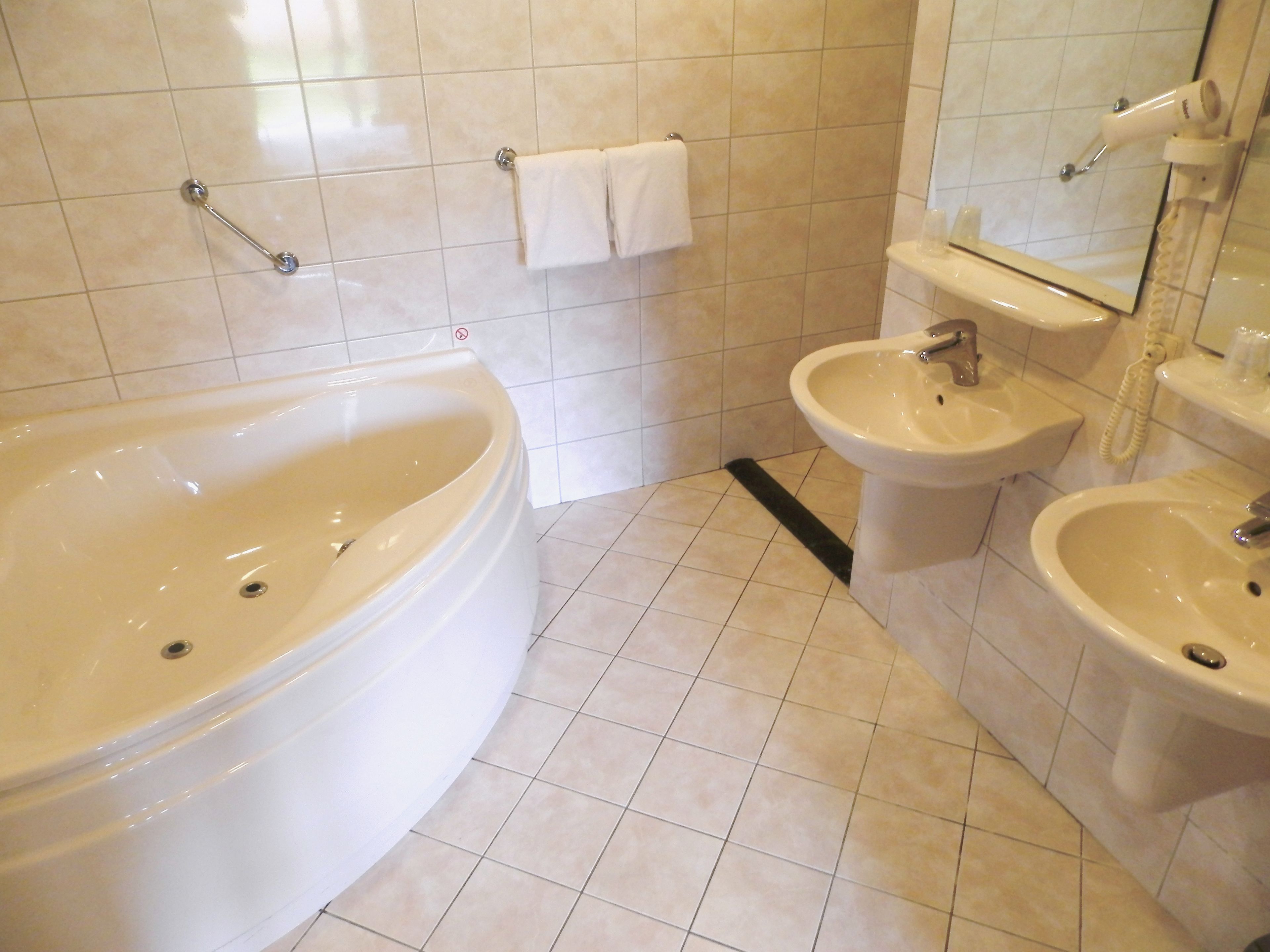 A bathroom with a bathtub, two sinks, and a toilet.