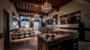 A spacious room with a large wooden table, multiple chairs, a chandelier, and a painting on the wall. - Fletcher Landgoedhotel Renesse (Renesse)