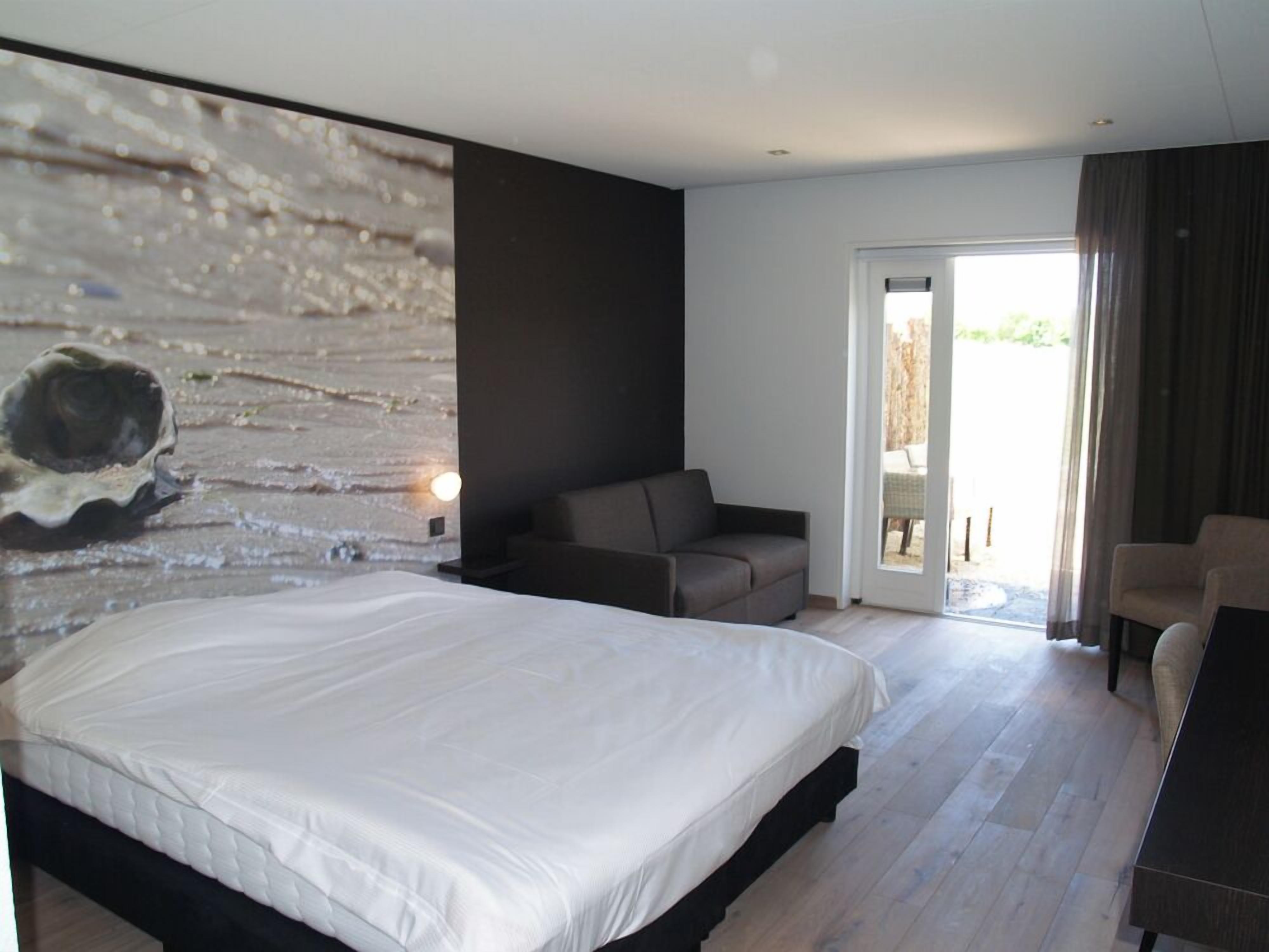 A modern bedroom with a large bed, a sofa, and a dining table.