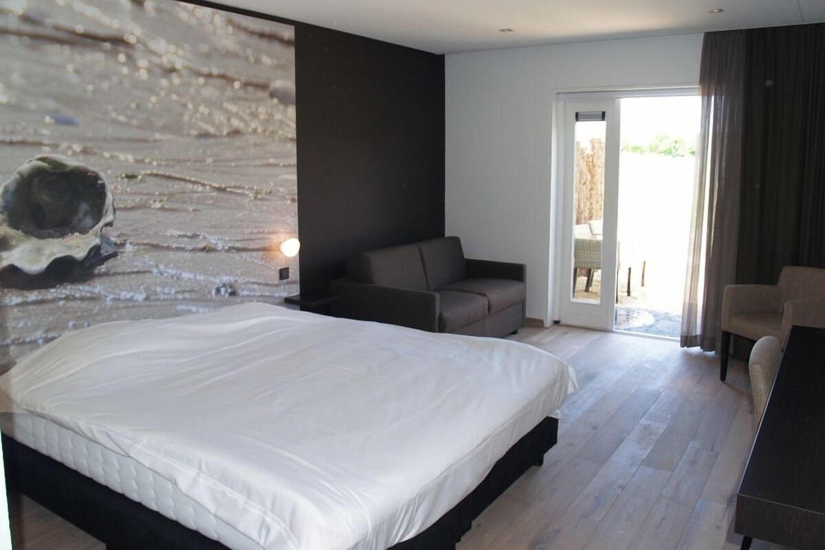 A modern bedroom with a large bed, a sofa, and a dining table.