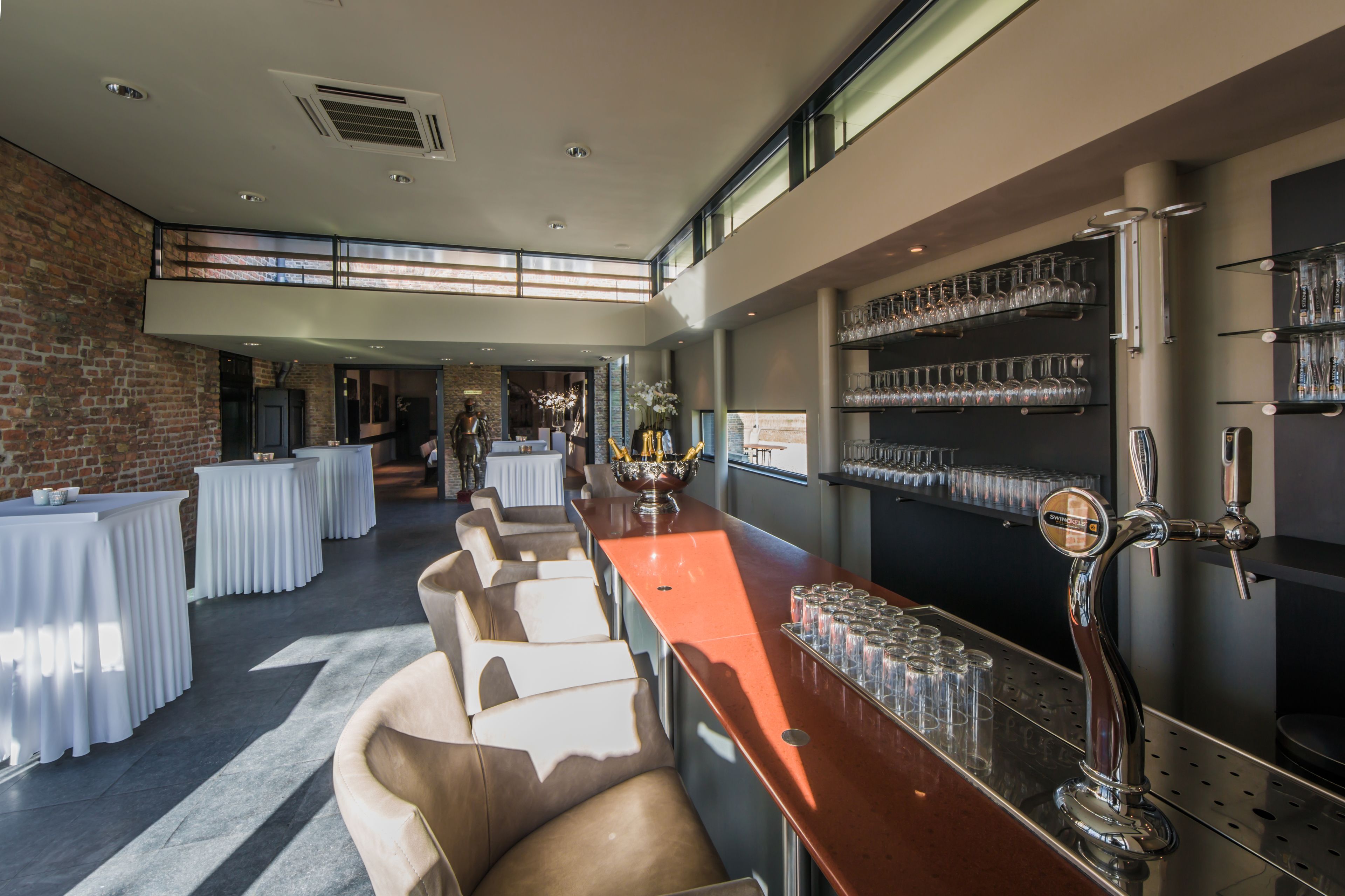 A modern bar area with a long counter, multiple seating options, and a brick wall.