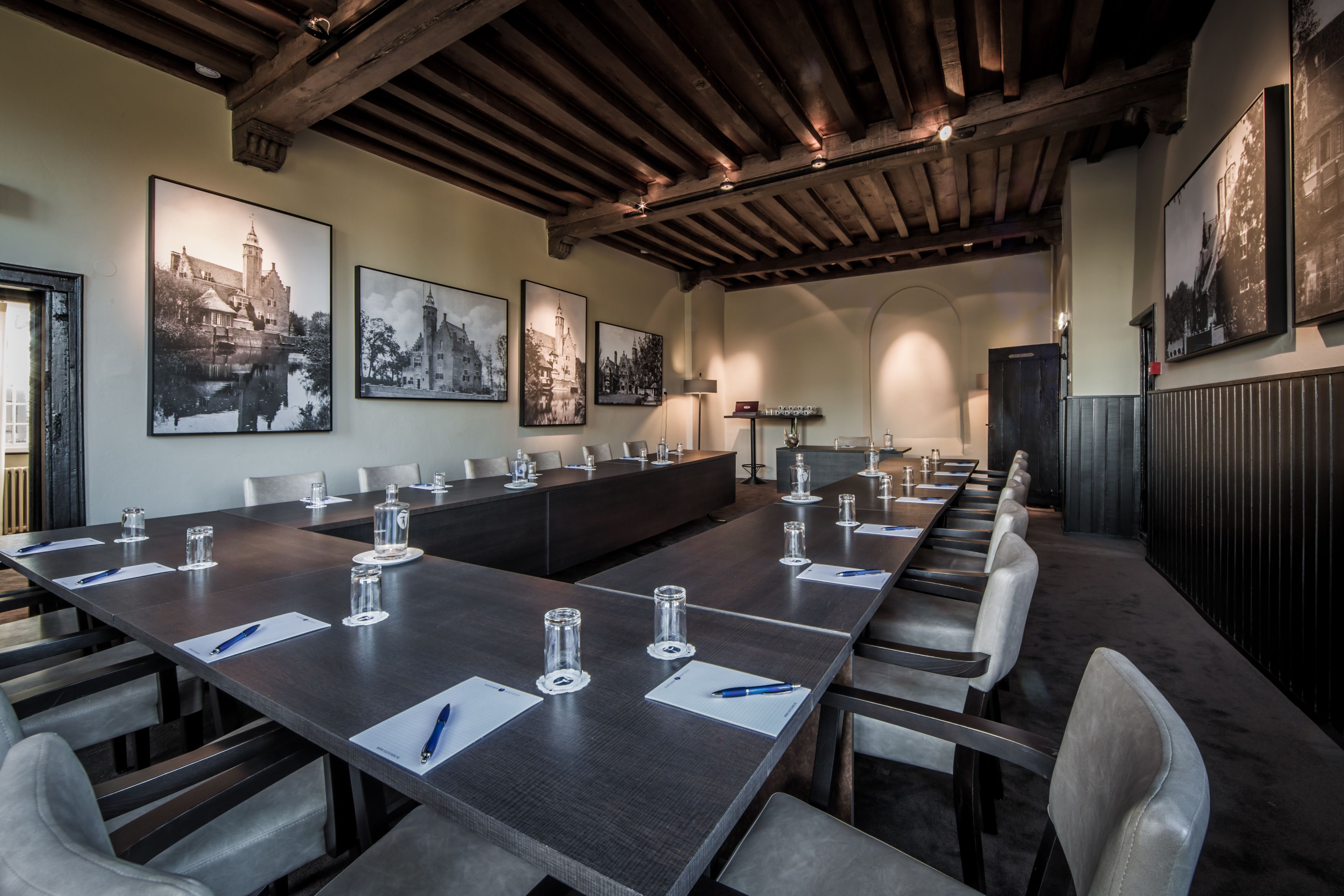 A conference room with a long table, chairs, and framed pictures on the walls.