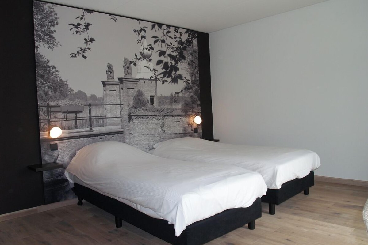 A bedroom with two beds, a mural on the wall, and a wooden floor.